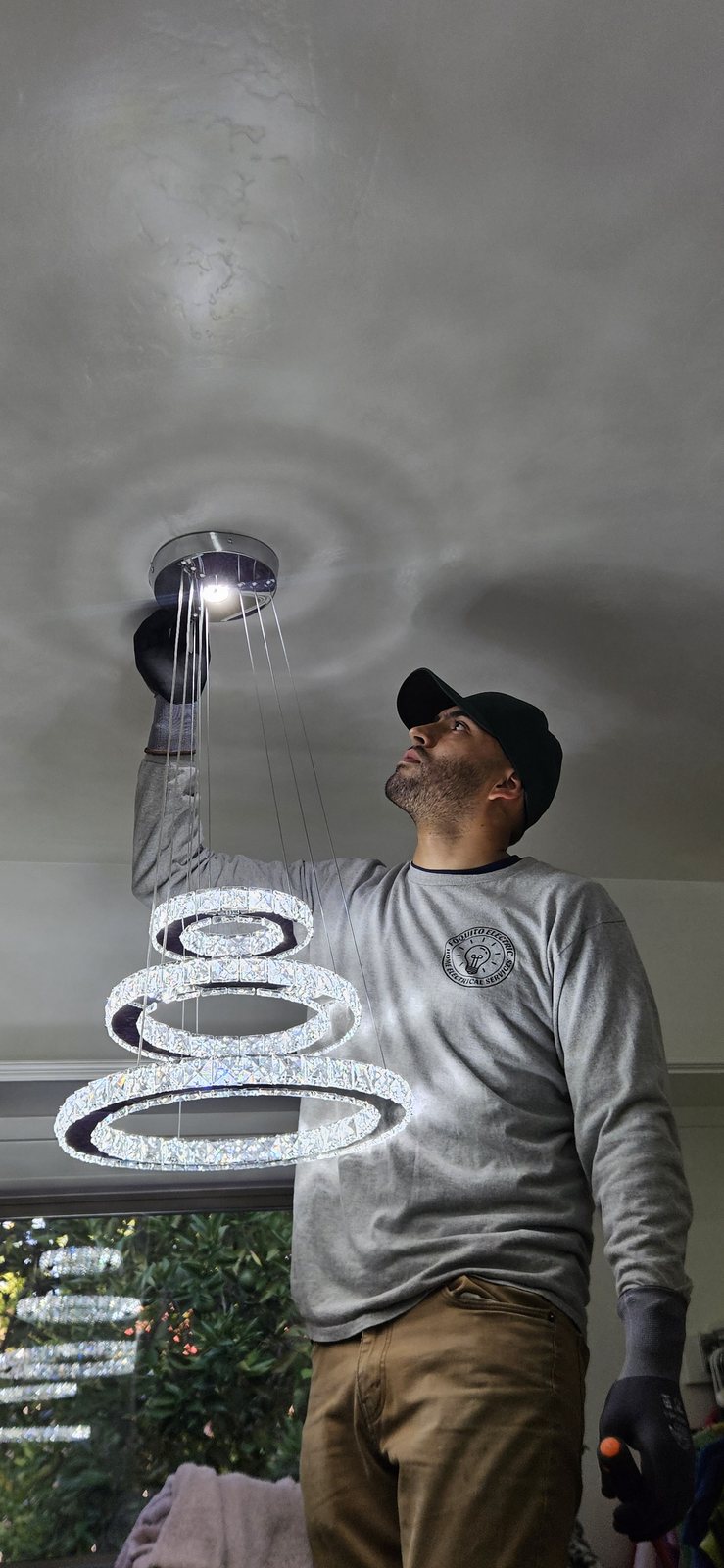 Foquito Electric installing a modern chandelier